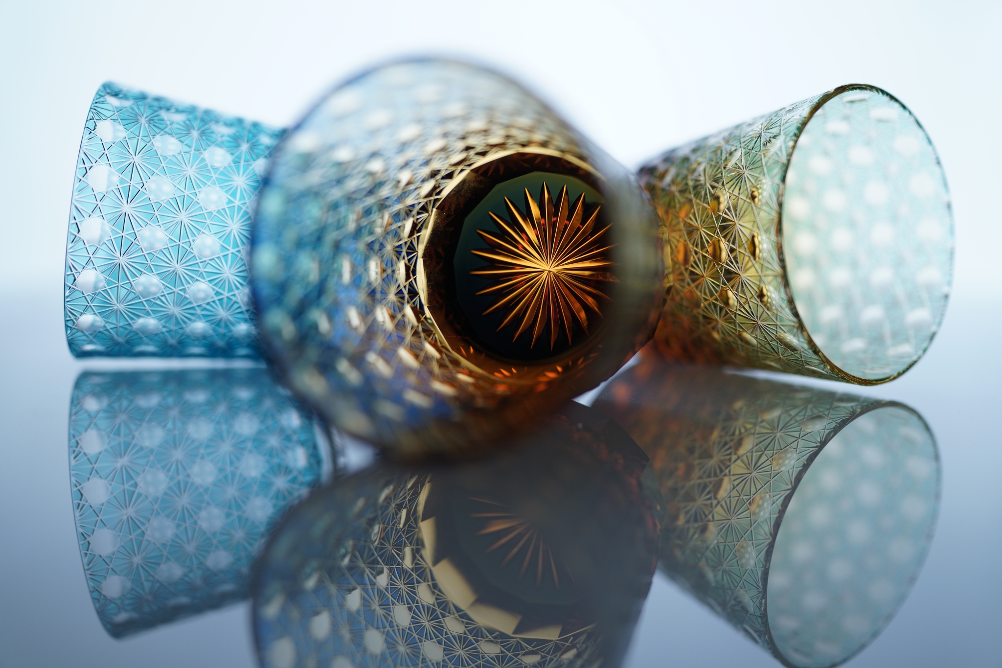 Three crystal glasses resting on a reflective surface