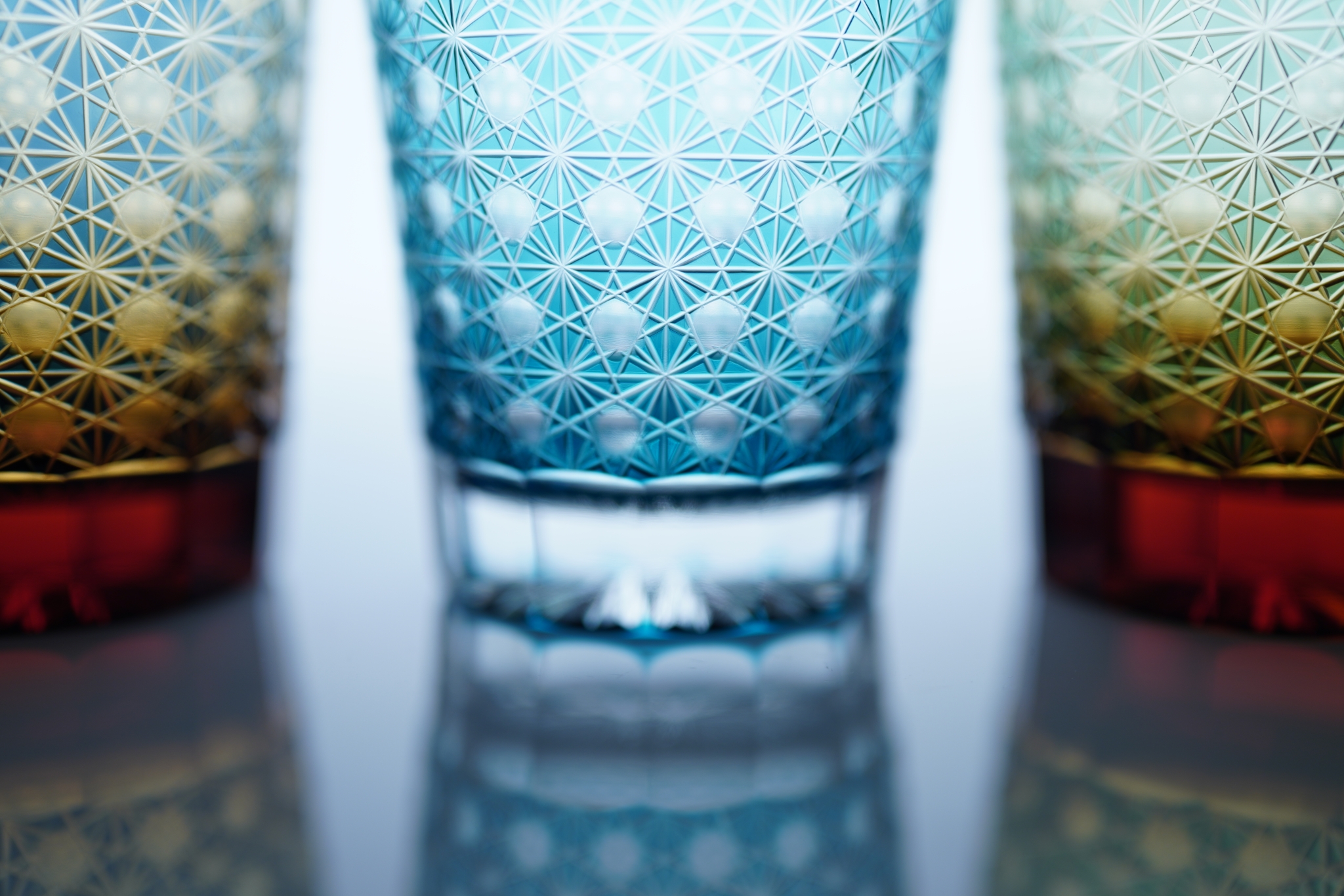 Close-up of the base of three crystal glasses placed on a reflective surface