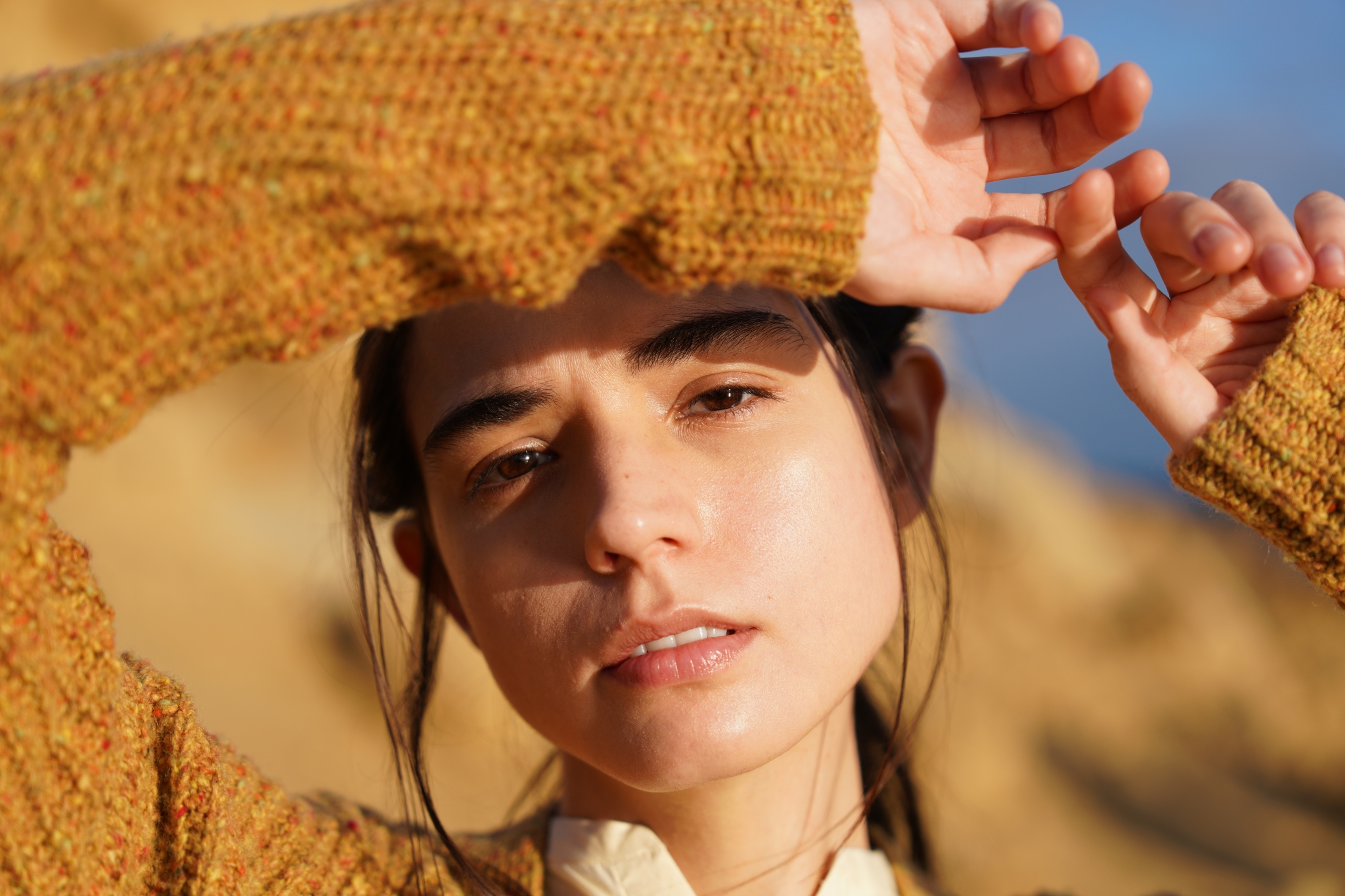 Portrait of a female model with her arm raised to her forehead