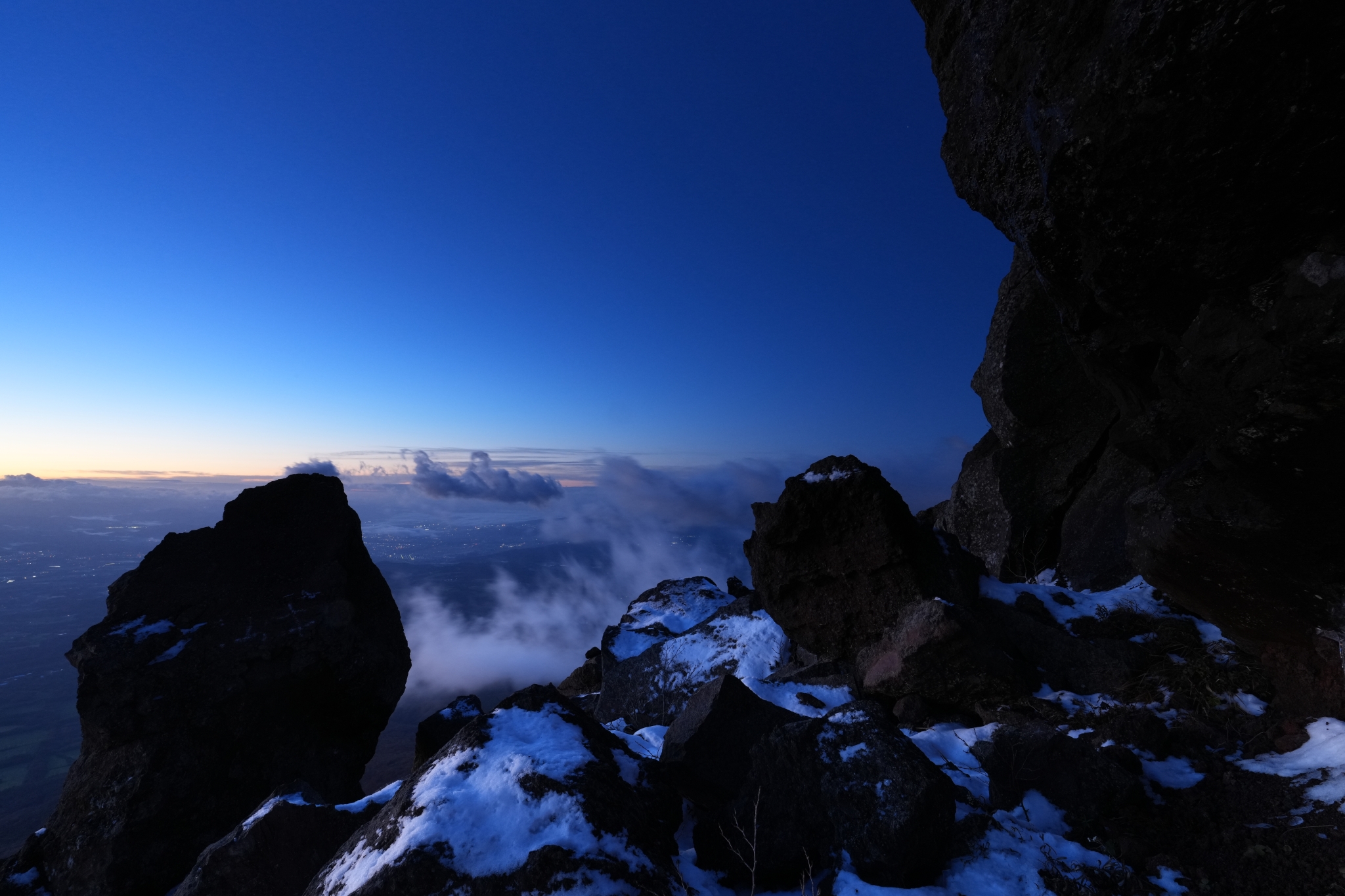 A spectacular view from a rocky area covered with snow at a high altitude.