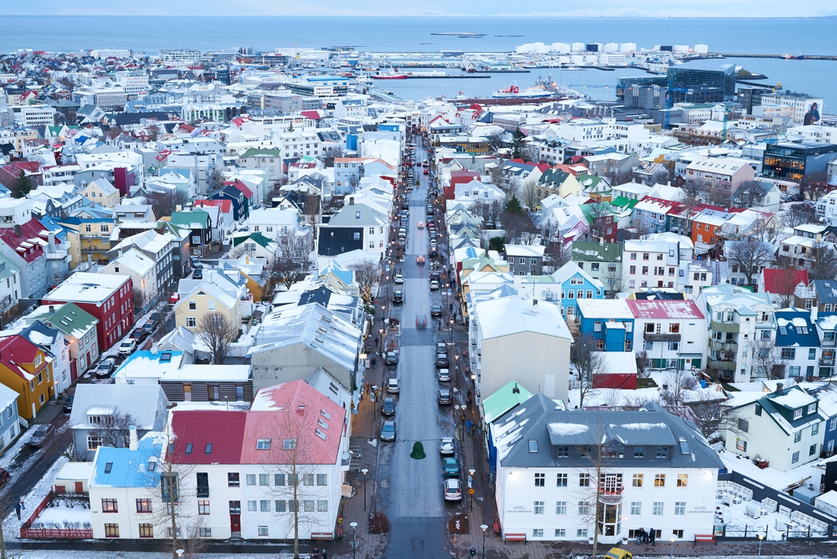 Aerial shot of port town with many buildings of different colours and ocean in background