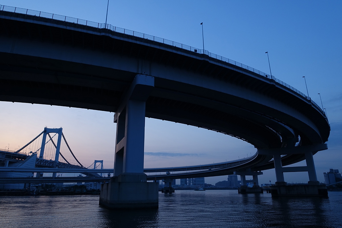 Shot of curved road bridge over water with suspension bridge in the background