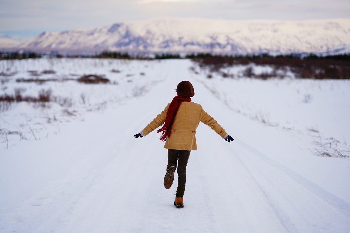 Rear view of child running down road in snow