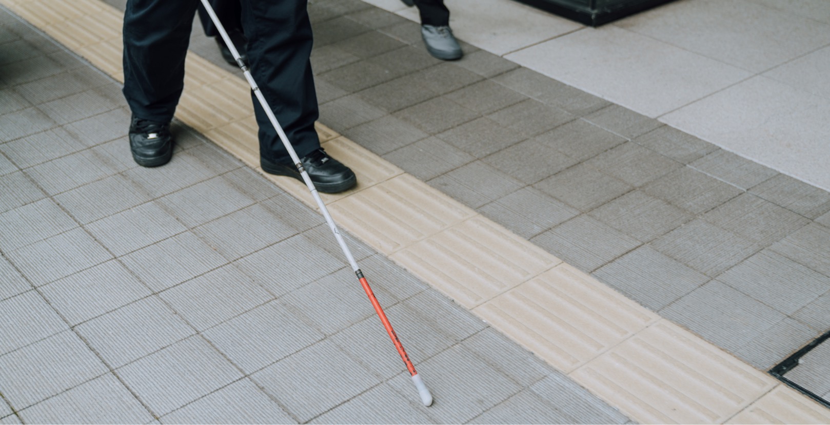 A picture of feet working on the yellow tiled floor, with a white cane.