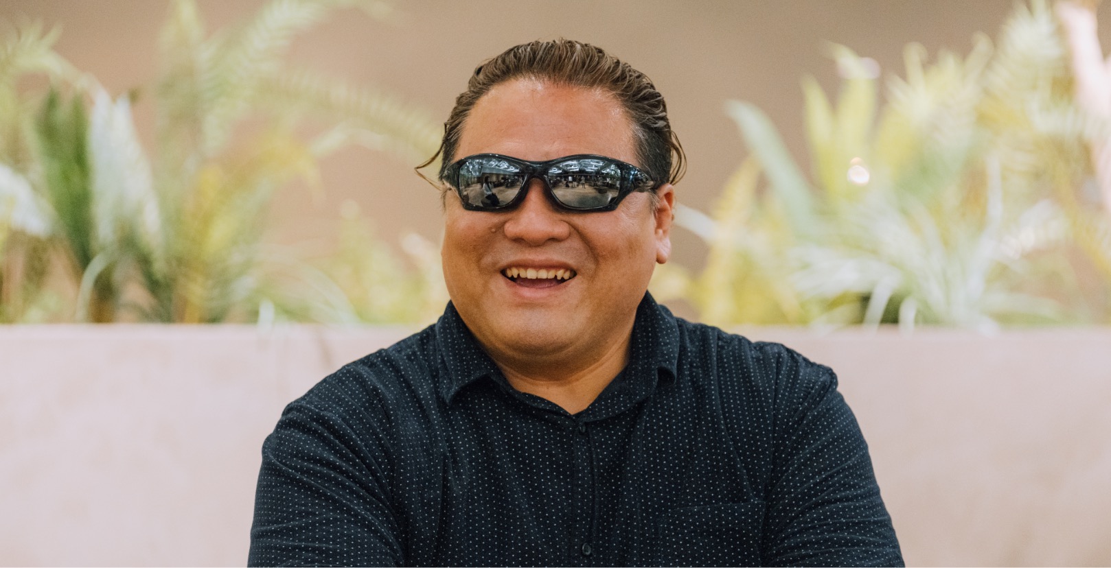 A male with sunglasses talking and smiling.