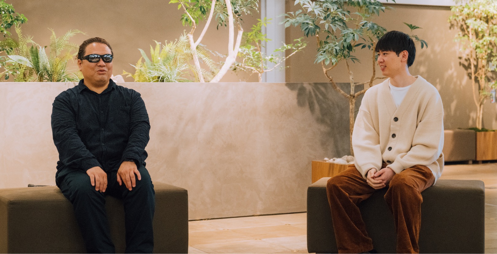 a male with sunglasses sitting and talking to the other male.