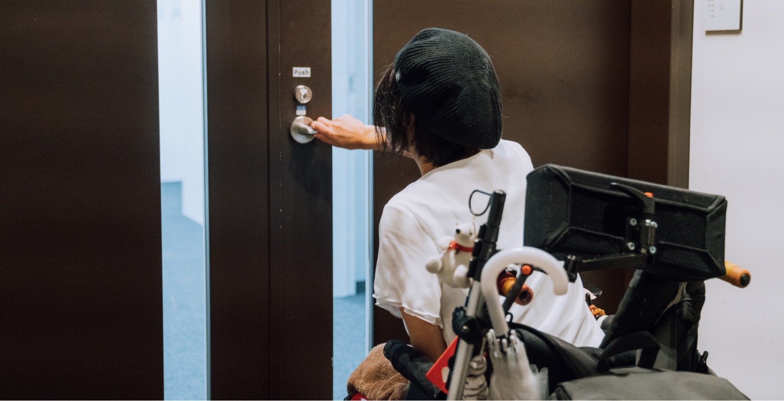 A female on a wheelchair opening a door.