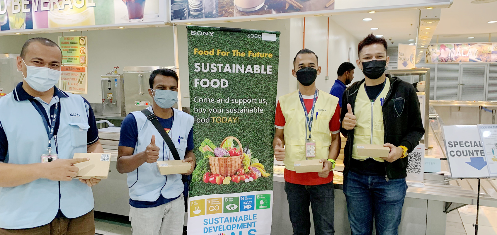 Employees lined up in front of a banner that reads "Sustainable Food"