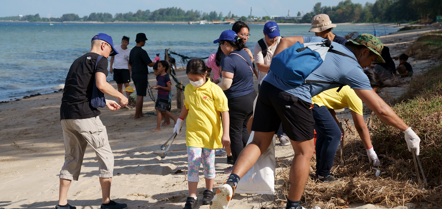 Employees are cleaning up at the beach with some children