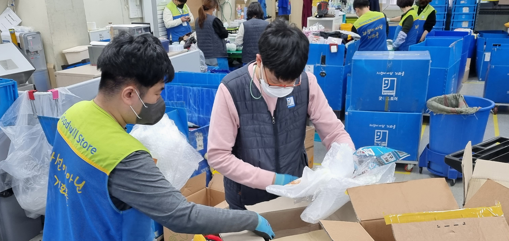 Employees are surrounded by many boxes, sorting through donated goods