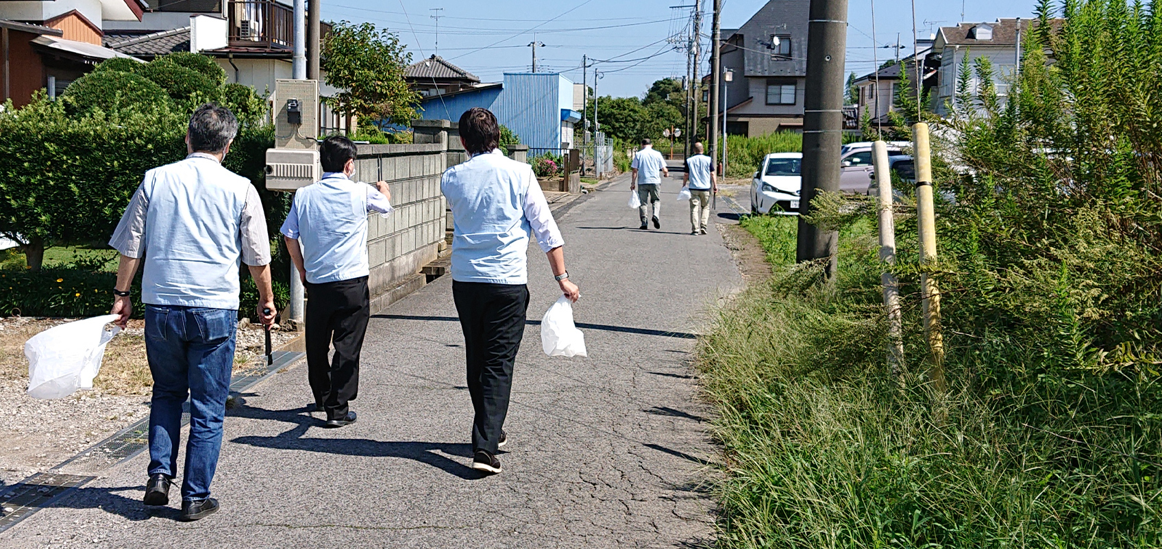 Employees picking up trash along the side of the sidewalk